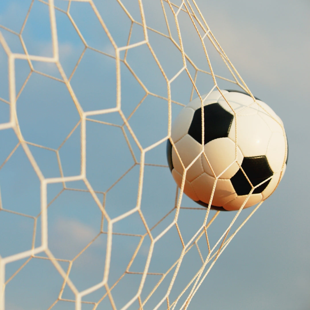 Soccer ball in the net against a blue sky